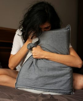 A woman sitting on a bed holding a pillow