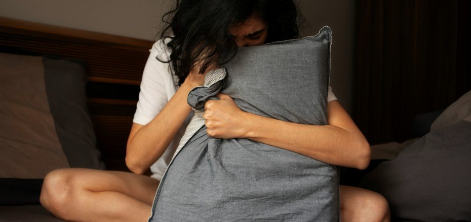 A woman sitting on a bed holding a pillow